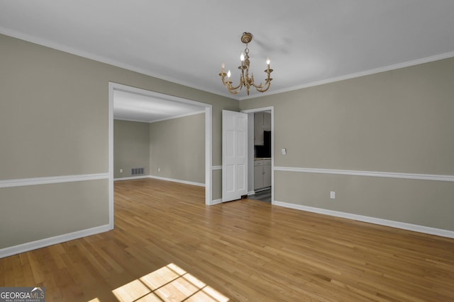 unfurnished dining area with light wood finished floors, baseboards, visible vents, crown molding, and a notable chandelier