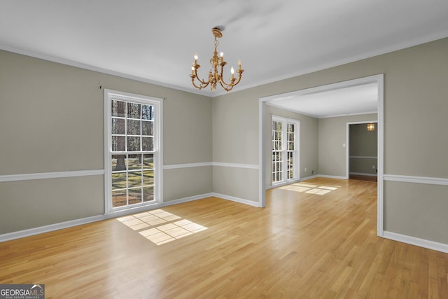 unfurnished dining area with baseboards, a chandelier, wood finished floors, and ornamental molding