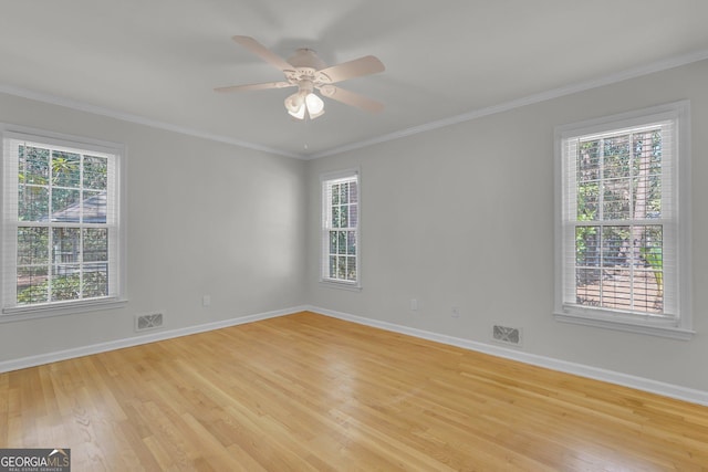 empty room featuring ornamental molding, a wealth of natural light, light wood-style floors, and baseboards