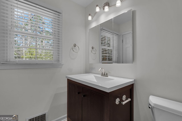 half bathroom with visible vents, vanity, and toilet