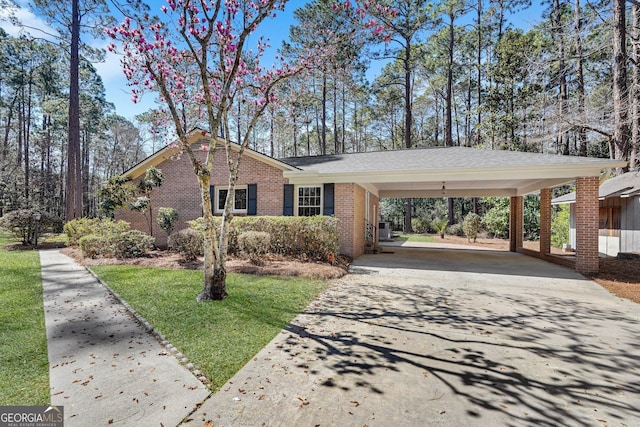 view of front facade featuring driveway, brick siding, central air condition unit, a carport, and a front yard