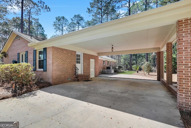 exterior space featuring entry steps, an attached carport, brick siding, concrete driveway, and crawl space