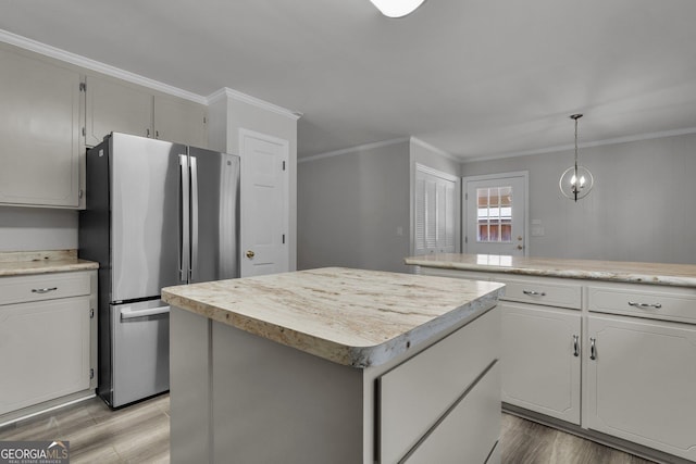 kitchen with a center island, freestanding refrigerator, light countertops, crown molding, and light wood-style floors