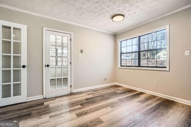 spare room featuring baseboards, plenty of natural light, wood finished floors, and crown molding