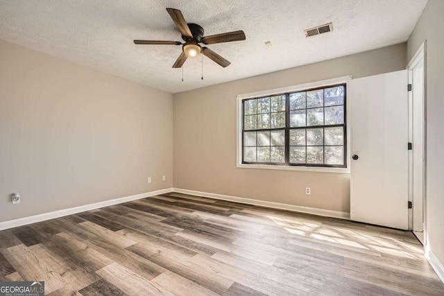 unfurnished bedroom with baseboards, a textured ceiling, visible vents, and wood finished floors