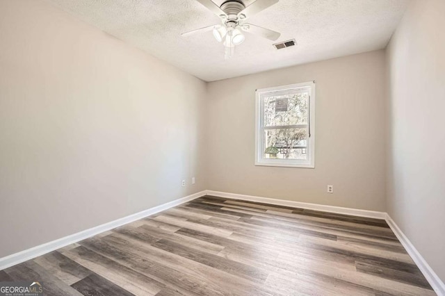 spare room with baseboards, a textured ceiling, visible vents, and wood finished floors