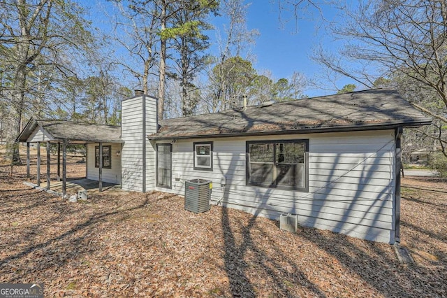 back of house with a chimney and central AC