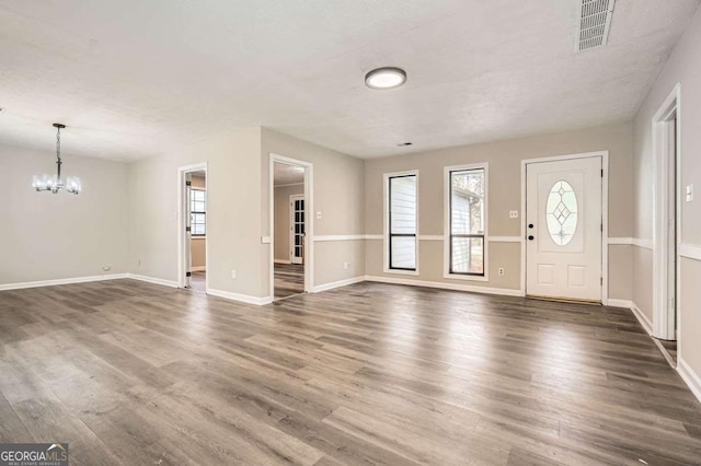 foyer with a healthy amount of sunlight, visible vents, a chandelier, and wood finished floors