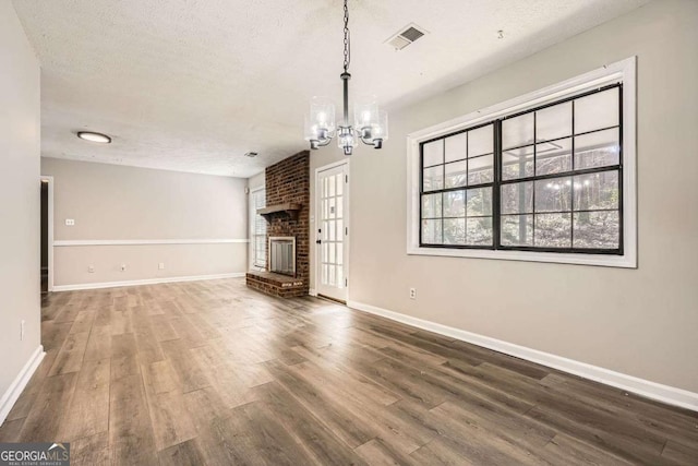 unfurnished living room featuring a textured ceiling, a fireplace, wood finished floors, and baseboards