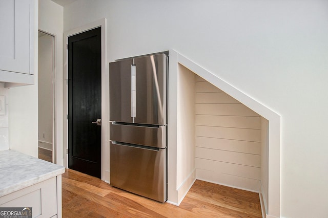 kitchen featuring light countertops, light wood-style flooring, freestanding refrigerator, and white cabinets