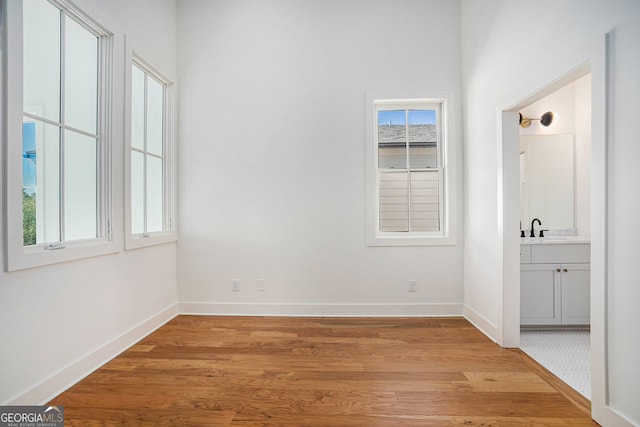 empty room featuring a sink, light wood-style flooring, and baseboards