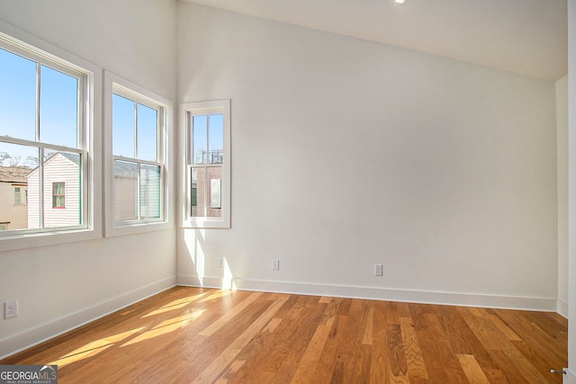 spare room with baseboards, light wood-style flooring, and a healthy amount of sunlight