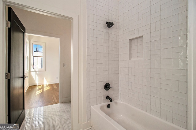 full bath featuring washtub / shower combination, baseboards, and wood finished floors