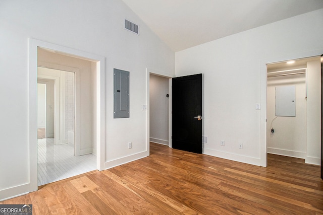 unfurnished bedroom with visible vents, wood finished floors, high vaulted ceiling, electric panel, and baseboards