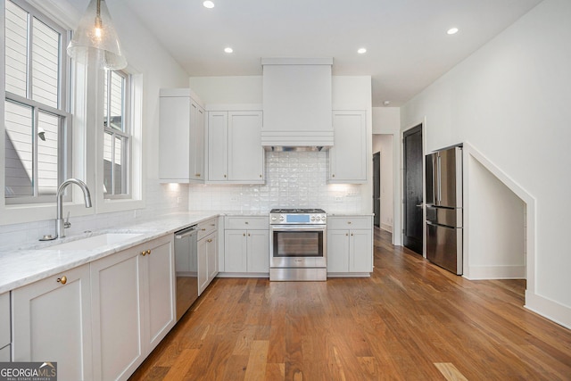 kitchen with stainless steel appliances, a sink, decorative backsplash, and custom exhaust hood