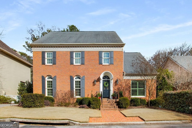 view of front of home with brick siding and roof with shingles