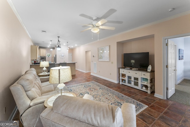 living area featuring a ceiling fan, baseboards, visible vents, and crown molding