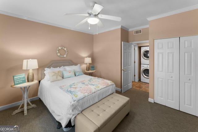 carpeted bedroom with a closet, visible vents, ornamental molding, stacked washing maching and dryer, and baseboards