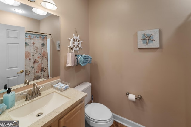 bathroom with toilet, curtained shower, baseboards, and vanity