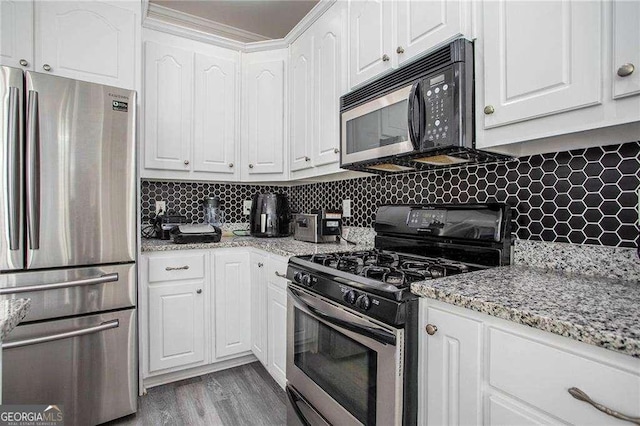 kitchen featuring stainless steel appliances, tasteful backsplash, wood finished floors, white cabinets, and light stone countertops