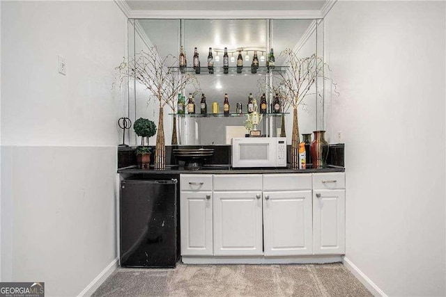 bar with white microwave, light carpet, wet bar, baseboards, and fridge