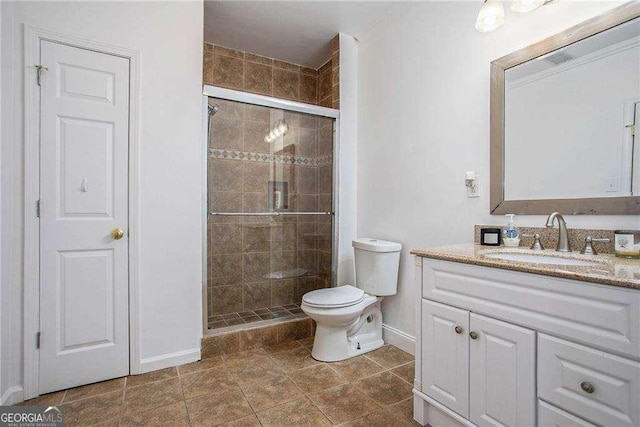 bathroom featuring toilet, a shower stall, baseboards, and vanity