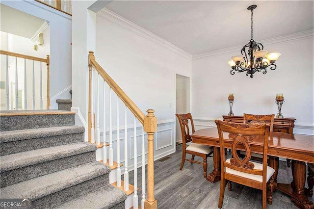 dining area featuring wainscoting, stairway, ornamental molding, wood finished floors, and a chandelier