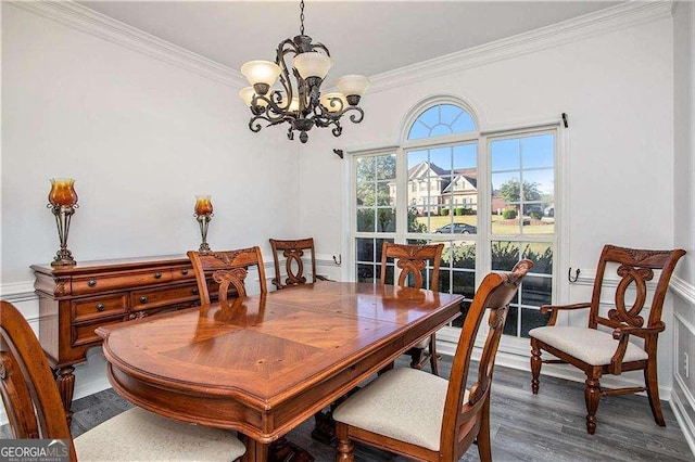 dining area with a chandelier, ornamental molding, and wood finished floors