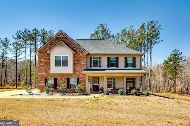 view of front of house with brick siding, covered porch, and a front yard