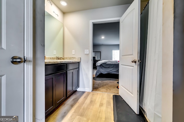 bathroom featuring ensuite bath, wood finished floors, and vanity