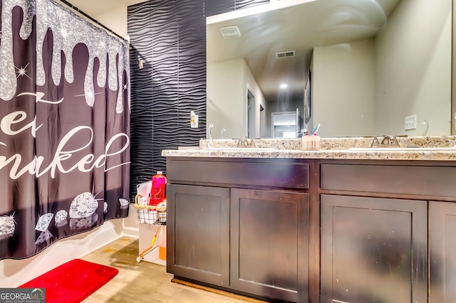 full bath with double vanity, visible vents, wood finished floors, and a sink