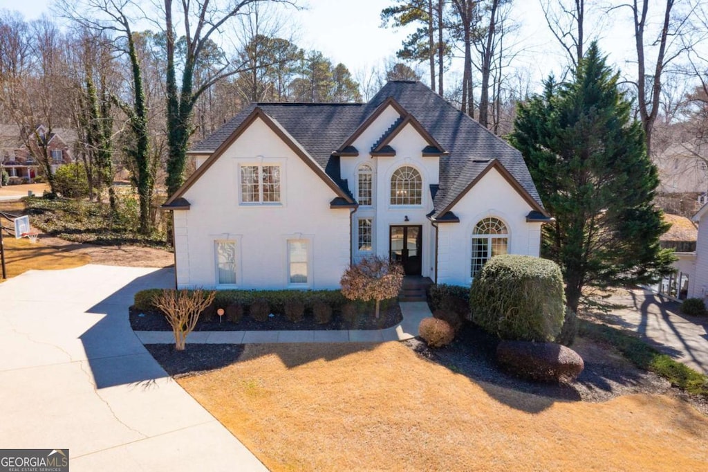 french provincial home with driveway, a shingled roof, and stucco siding