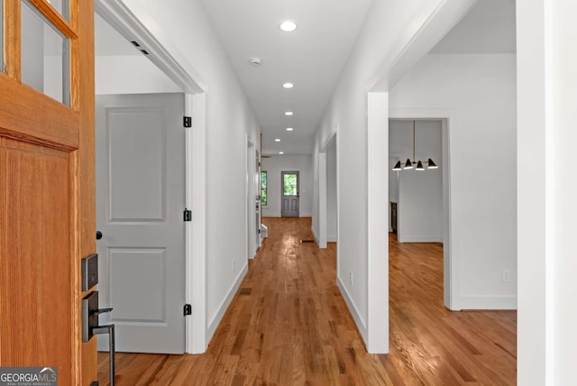 hallway featuring baseboards, wood finished floors, and recessed lighting