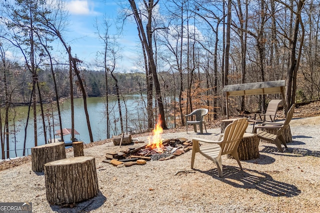 view of yard featuring a water view, a fire pit, and a view of trees