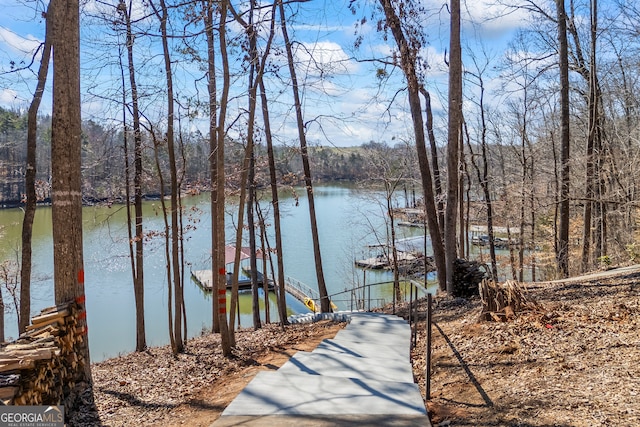 view of dock with a water view and a forest view