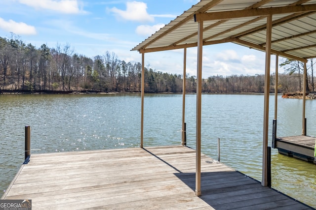 view of dock with a water view and a wooded view