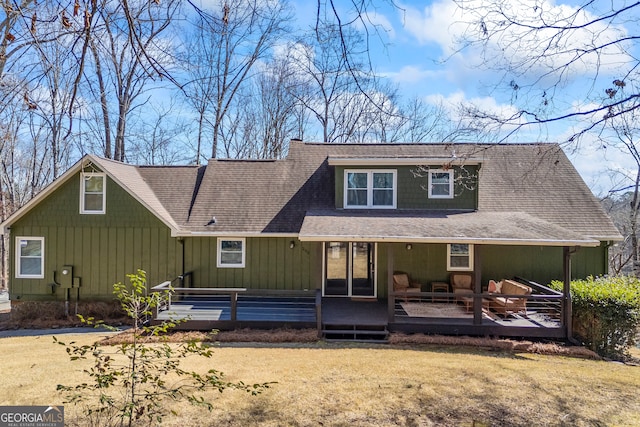 rear view of property featuring a shingled roof, a lawn, and a wooden deck