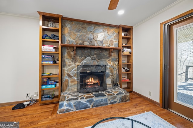 living room with built in features, a fireplace, crown molding, wood finished floors, and baseboards