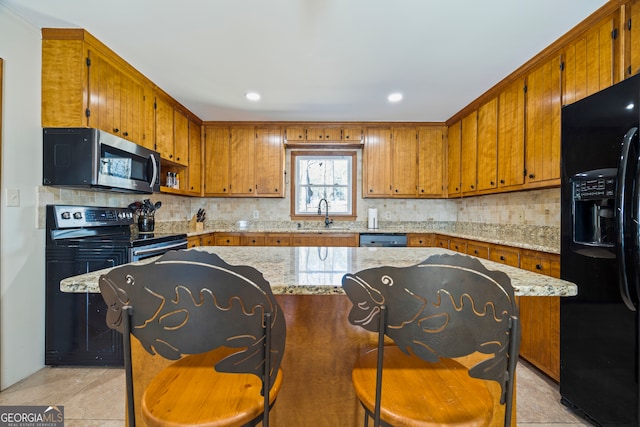 kitchen with appliances with stainless steel finishes, decorative backsplash, a sink, and brown cabinets