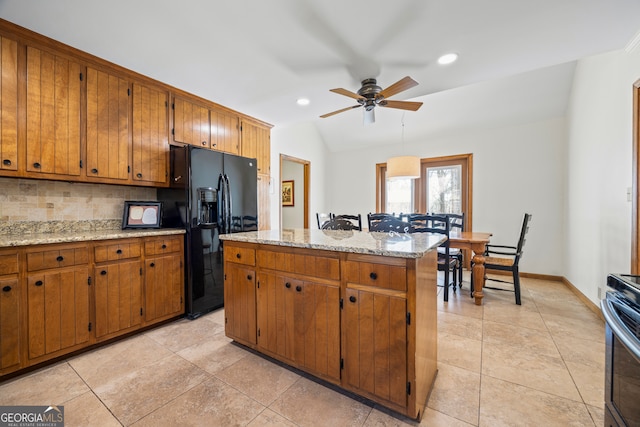 kitchen featuring lofted ceiling, tasteful backsplash, black fridge, and brown cabinets