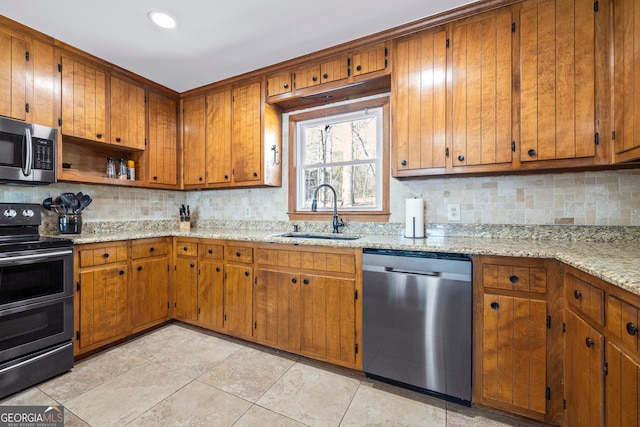 kitchen featuring stainless steel appliances, tasteful backsplash, a sink, and brown cabinets