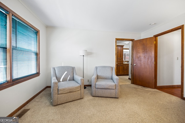 sitting room featuring light carpet, ornamental molding, visible vents, and baseboards