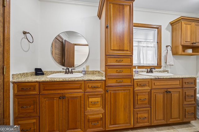 bathroom featuring ornamental molding, a sink, toilet, and double vanity