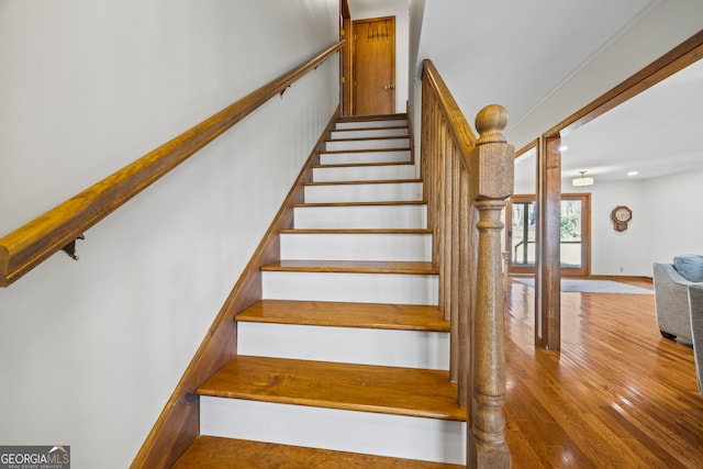 stairs featuring decorative columns and wood finished floors