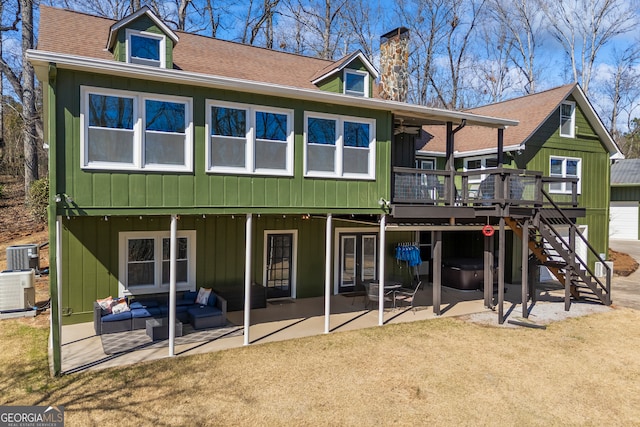 back of house featuring a wooden deck, stairs, roof with shingles, and a patio