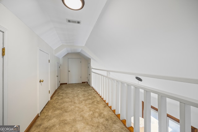 corridor featuring lofted ceiling, light carpet, and visible vents