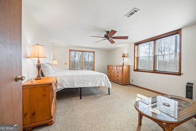 bedroom featuring heating unit, visible vents, a ceiling fan, light carpet, and baseboards