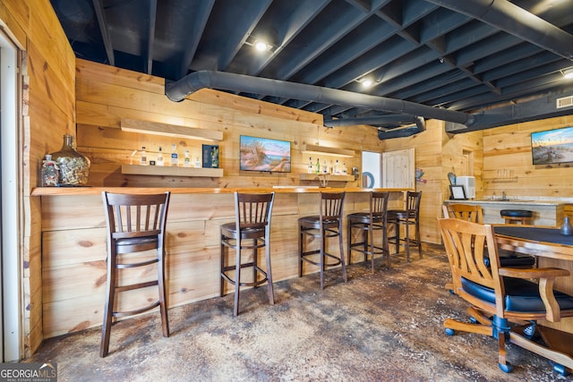 bar with a dry bar, a sink, and wooden walls