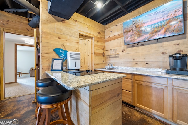 kitchen with wood walls, light stone counters, and black electric cooktop