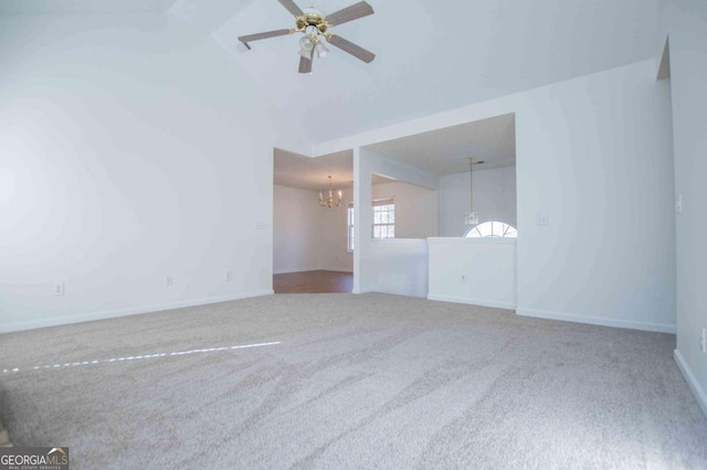 spare room with carpet, vaulted ceiling, baseboards, and ceiling fan with notable chandelier